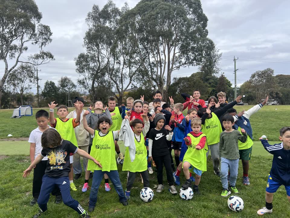 Holiday program players in bibs celebrating with their footballs