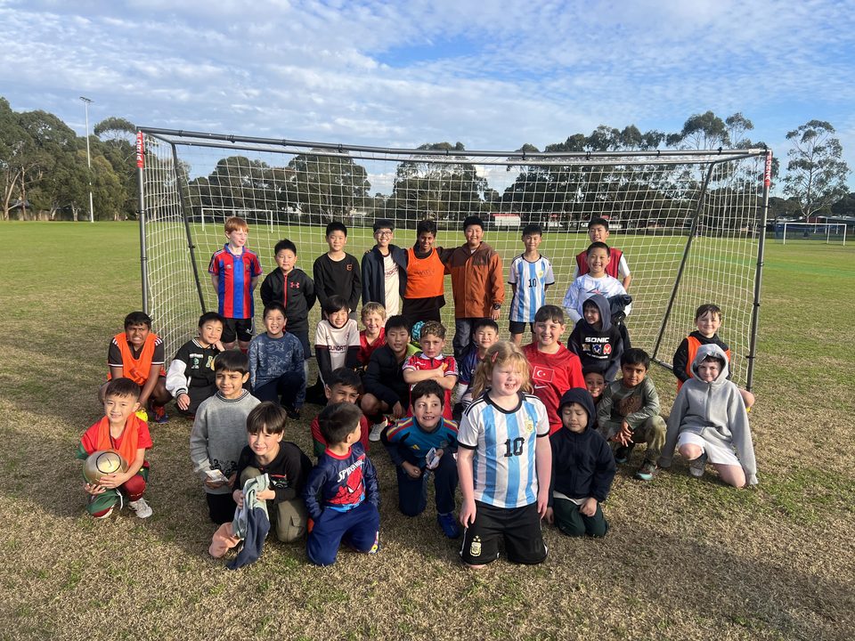 Holiday program players around a portable goal on the park