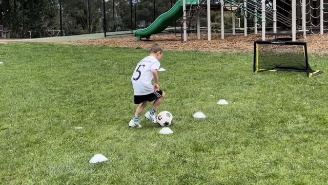 A young player working through a one-on-one drill with cones