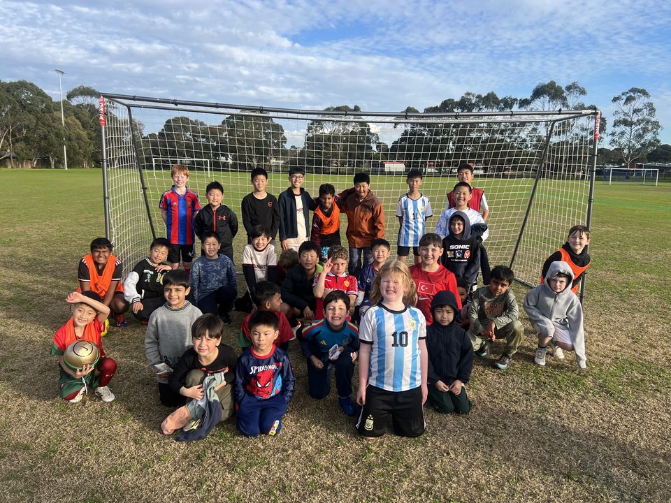 Holiday program players around a portable goal on the park